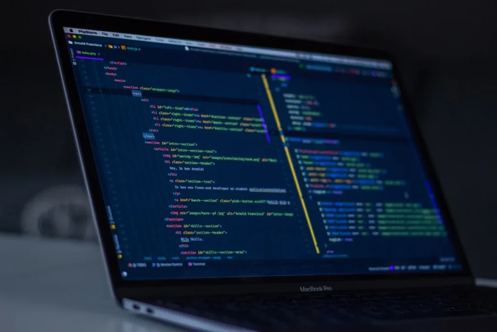 Layar laptop menampilkan kode program untuk aplikasi web custom